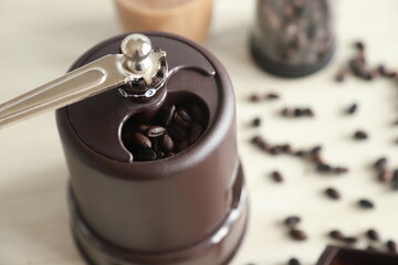 Manual coffee grinder with ground coffee beans on a table