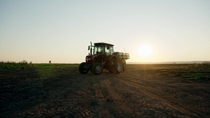 Fototapeta premium preparation process of spraying with chemicals and pesticides fields with potatoes. Growing potatoes in fields and cultivating vegetables. tractor pulls barrel with irrigation system behind it.