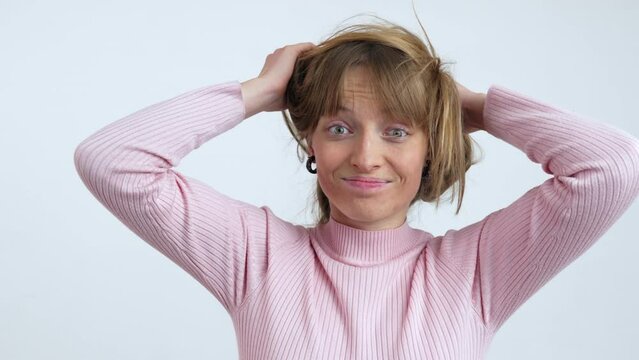 Crazy fun happy woman messing up her long hair and looking into the camera. Itchy head. isolated on white background slow motion portrait shot