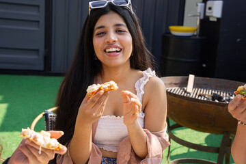 Happy Young indian girl eating pizza at cafe restaurant outdoor. Summer season. Closeup.