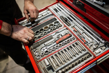 Dirty mechanic hands choosing best wrench for working with car repair