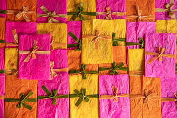 Multi-colored envelopes decorated with ribbons and bows are stacked together on the table, top...