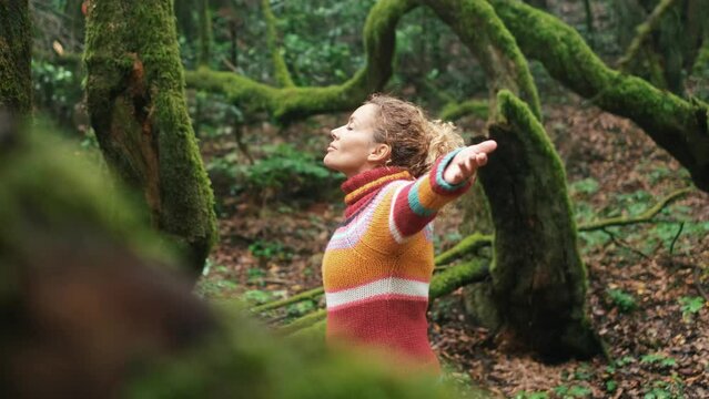 Happy and serene woman standing and opening arms in the nature park forest. Outdoors joy leisure activity people. Female outstretching arms and hug nature with love and environment lifestyle concept