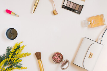 A composition with women's accessories, cosmetics and yellow flowers on a colored background. The concept of a beauty blogger