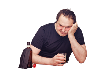 Angry man drinks alcohol sitting with a bottle of whiskey at the kitchen table, isolated on a white background. Problems with alcoholism during the epidemic, isolation and lockdown
