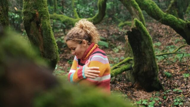 One healthy woman alone in the green forest hugging herself with love and positive lifestyle. Female people and mindful wellbeing life. Outdoors park leisure activity alone. Happiness and freedom