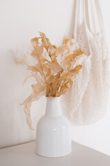 Dried flower in a white ceramic vase in the Scandinavian decor of a cozy home
