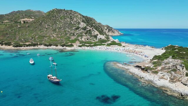 Punta Molentis Beach in Villasimius, Sardinia - Boats and Tourists in Turquoise Blue Sea and Small White Sandy Beach - Aerial 4k Circling