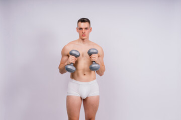Shirtless bodybuilder holding dumbell and showing his muscular arms.
