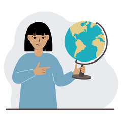 A woman holds a globe in his hand and points his finger at it. The concept of education, teacher, world conquest, ecology.