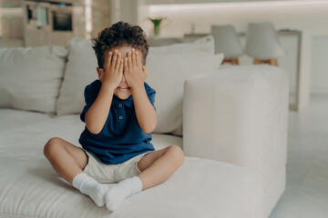 Small afro american boy playing hide and seek at home