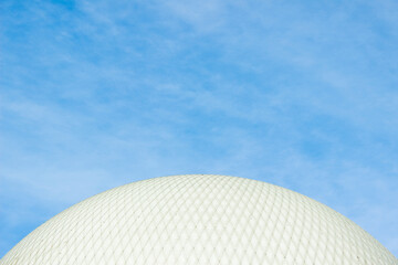 Part of a large white sphere. White ball view against the sky.