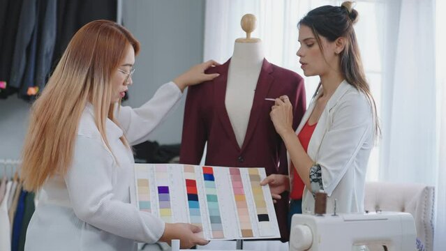 Two professional woman fashion designers collaborate to discuss and create a men suit. Choosing colors from the board to suit the requirements of the customers. in the tailor shop
