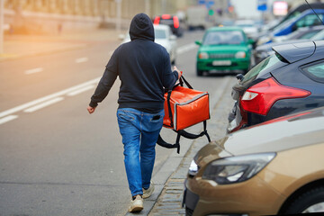 Delivery food to customers, contactless delivery service. Worker with thermal backpack delivering pizza at doorstep from restaurant, supermarket. Man courier delivers food and drink to customer