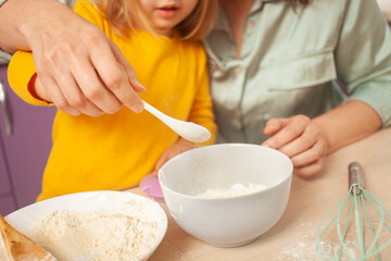 Grandmother and granddaughter prepare cake dough, spend time together, family relationships, love. pour sugar into a cup