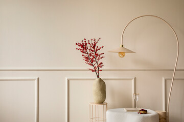 Interior design of living room interior with copy space, vase with rowan, white pouf, beige rug, round coffee table, stylish lamp, wall with stucco and personal accessories. Home decor. Template.