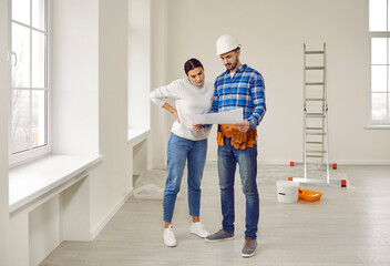 Finishing painting decorating work foreman builder supervisor in hardhat showing young woman...