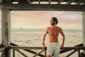 Relaxed and cheerful. Happy young bearded man resting on terrace near the sea.