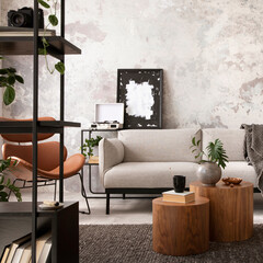 Modern composition of indiustral living room interior with mock up poster frame, gray sofa, round wooden coffee table, brown leather armchair, black desk, modern lamp, rack and personal accessories. 