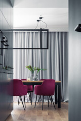 Stylish composition of kitchen and dining room open space interior. Minimalist ergonomic kitchen space. Velvet chairs, wooden table and personal accessories in the modern dining room. Template.