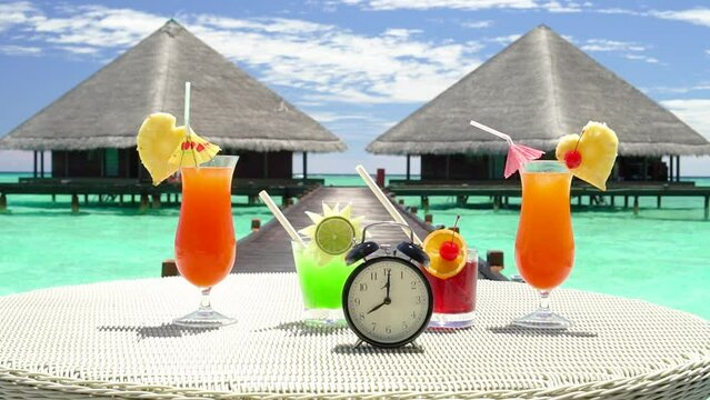 Summer vacation concept. Time to relax. Black Alarm clock with and bright cocktails on the sea background. clock shows 8 a.m.