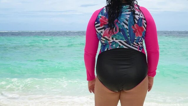 Happy plus size woman dancing on the beach during summer vacation, her face is not visible. - Lifestyle concept of curvy self-confident people,