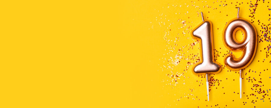 Gold candles in the form of number nineteen on yellow background with confetti. 19 years celebration. Greeting banner.