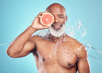 Senior man, skincare and portrait with grapefruit in studio for wellness, grooming or hygiene on blue background. Fruit, product and elderly man in water splash for beauty, luxury and facial isolated