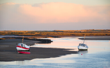 Fishing boats at low tide  on the sea creek at Burnham Overy Staithe, Norfolk at sunrise - obrazy, fototapety, plakaty