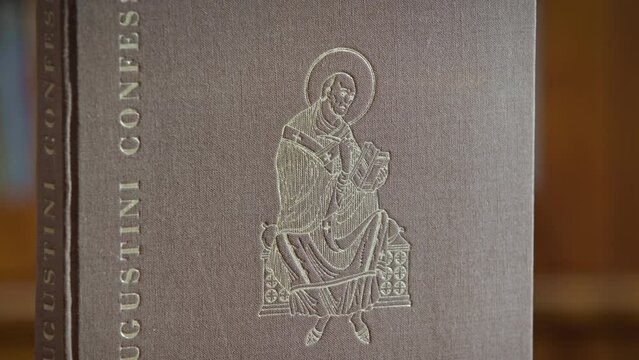 Close up of an book cover with the title Augustini Confessiones, a pisture of st. Augustine on the front side of the book.
