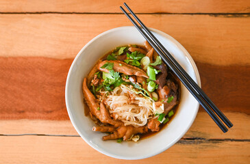 chicken noodles with chicken feet and chicken wings and vegetable on soup bowl , Thai food