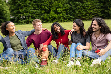 Fototapeta premium Multicultural group of students studying together in harmony, sitting in the campus park. Their unity and focus representing the inclusive and empowering atmosphere of higher education