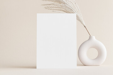 Fototapeta White invitation card mockup with a reed pampas decoration on a soft yellow background. 5x7 ratio, similar to A6, A5. obraz