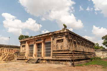Exterior facade of a mandapa hall of an ancient Hindu temple in Tamil Nadu with blue skies above.