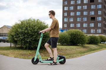 White man riding an electric scooter in the city showcases a trendy and efficient mode of...