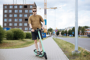 White man riding an electric scooter in the city showcases a trendy and efficient mode of...