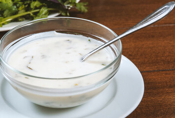 yogurt soup with herbs in a plate on a wooden table.spas