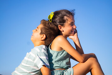 Two relaxed kids against blue sky at summer