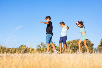 Fototapeta na wymiar Three kids on summer vacation playing against a blue sky