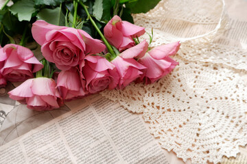 Beautiful pink dusty rose bouquet on English newspaper background. Vintage floral background for Mother's day, Women's day, wedding and Valentine day. 