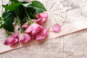 Beautiful pink dusty rose bouquet on English newspaper background. Vintage floral background for Mother's day, Women's day, wedding and Valentine day. 