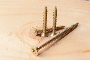 Self-tapping screws on the background of a wooden board. Close-up