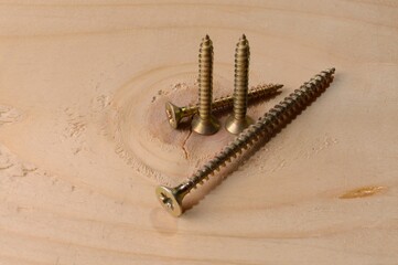 Self-tapping screws on the background of a wooden board. Close-up