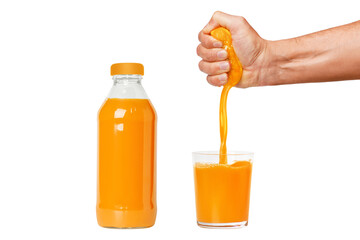A man's hand squeezes a ripe orange into a glass. A man is holding and squeezing an orange. Orange juice is pouring. Bottle with freshly squeezed orange juice. Isolated on white background.