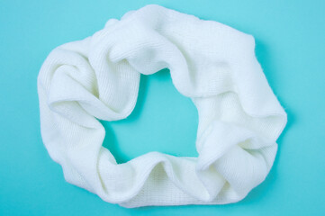 White knitted scarf snood on a blue background. View from above.