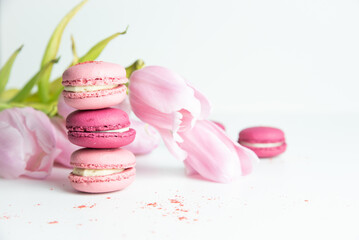 Stack of pink macaroons with pink tulips on white background