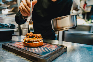 chef hand cooking cheeseburger on restaurant kitchen