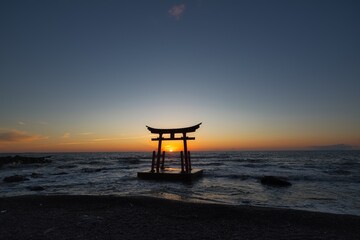 夕暮れの時海に沈む太陽が鳥居に入る瞬間