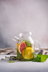 Glass teapot of hot healthy fruit tea with fresh ripe citrus, mint and  thyme