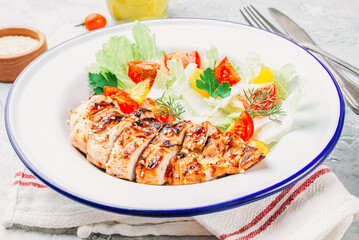 Fried chicken fillet and fresh vegetable salad of tomatoes over gray marble table. Grilled chicken breast. Healthy food.
